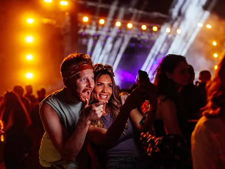 Two friends taking a selfie on a smartphone at a concert