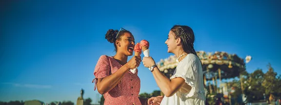 Shot of two happy young women eating ice cream together at a carnival