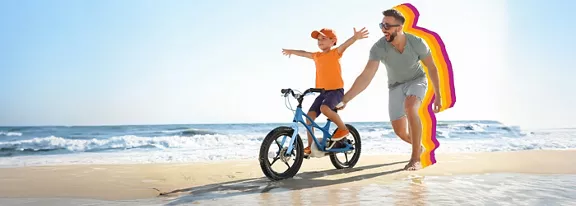 son riding a bike on the beach with his dad