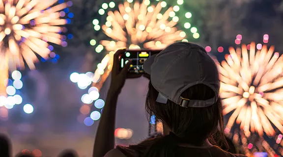 A young woman taking photos of fireworks