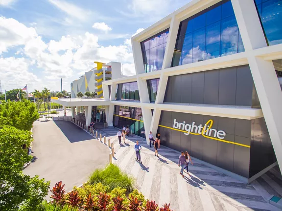 Exterior of Brightline Fort Lauderdale station with people walking in front of the building