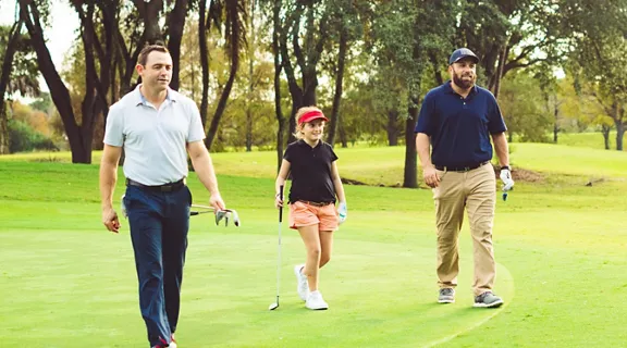 Two men and a young girl walking on the golf course