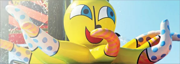 A bright yellow inflatable octopus with a smiling face dominates the scene. Its tentacles are decora