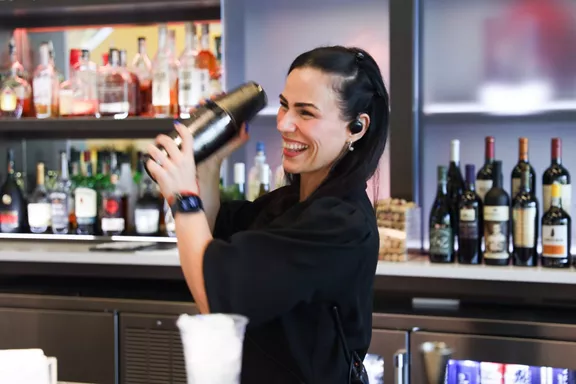 A young girl smiling while mixing a drink at the bar