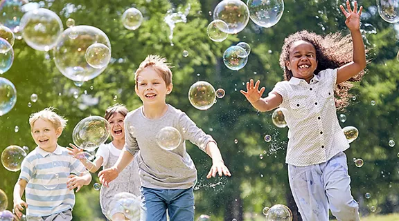 A group of children playing in a field chasing bubbles