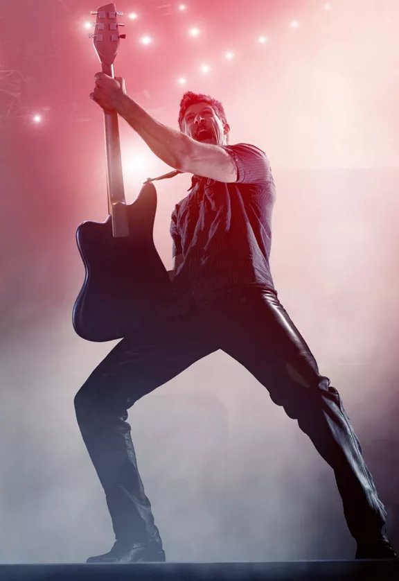 A performer playing a guitar on stage with smoke around
