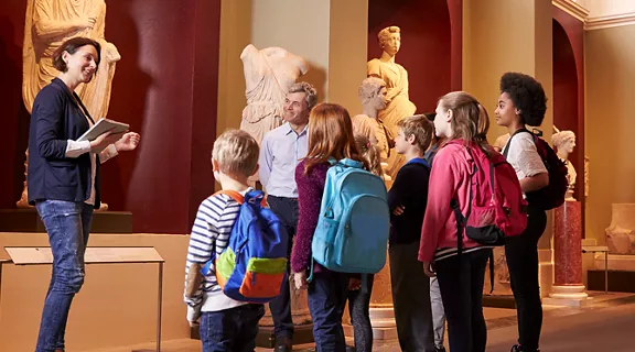A group of children listening to the librarian at the museum