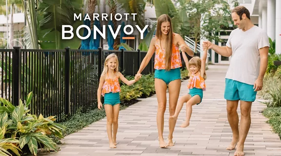 Happy couple with two kids walking along a resort pathway.