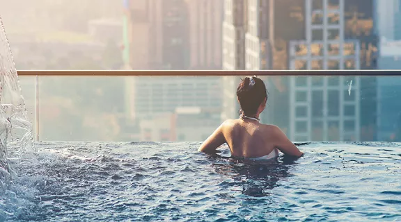A view of a woman swimming on the top floor looking out at the buildings