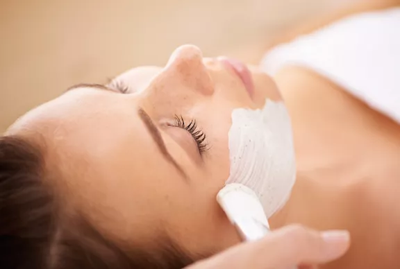 Closeup of a beauty therapist applying a face mask to a client