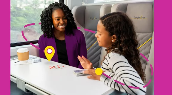 mother and daughter seated on train playing cards