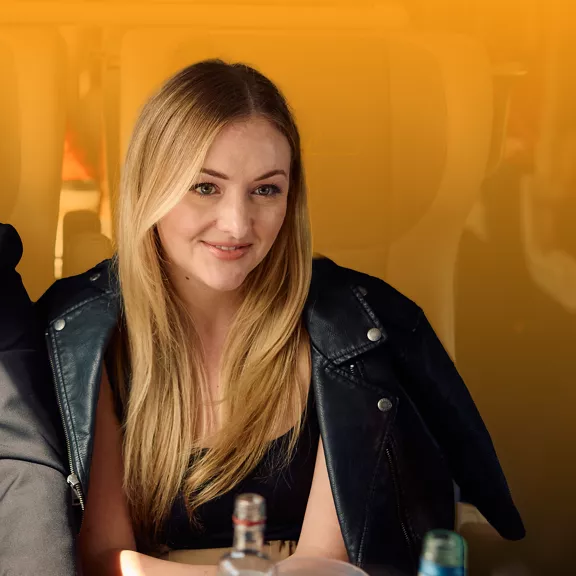 A woman smiling while taking a ride on a Brightline train.
