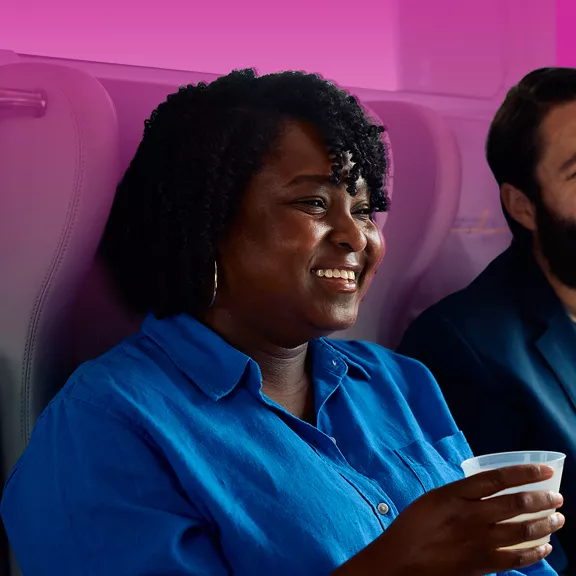 A woman relaxing with a drink while taking a ride on a Brightline train.