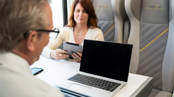 A man and a woman using their electronic devices onboard a Brightline train