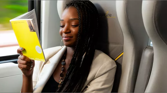 A woman sitting on a Brightline train reading
