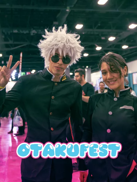 Two cosplayers in dark matching outfits pose together at an indoor convention. The word "OTAKUFEST" appears prominently in bright, playful lettering at the bottom of the image.