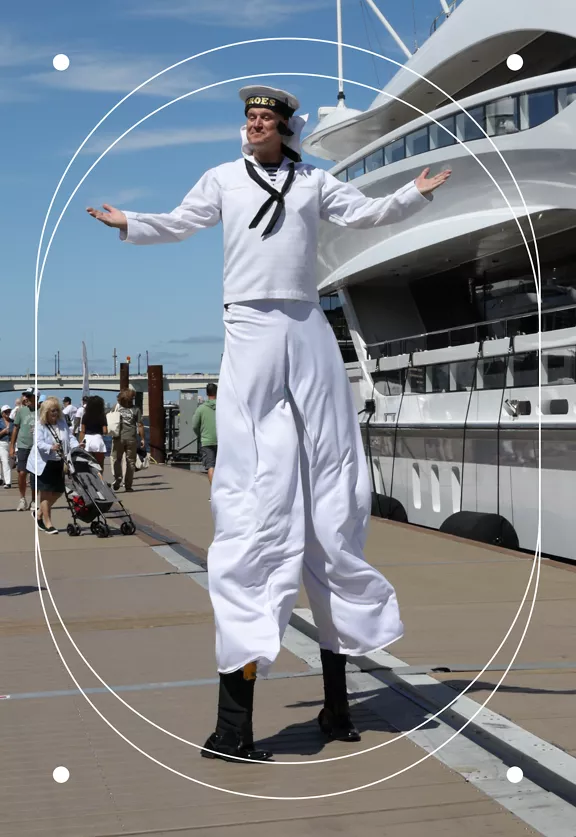 A man on stilts dressed as a sailor performing outside the Palm Beach International Boat Show.