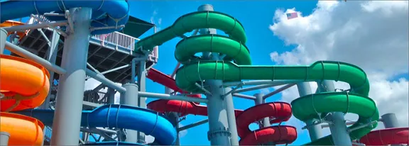 A group of brightly colored water slides twists around tall support structures at an outdoor water p