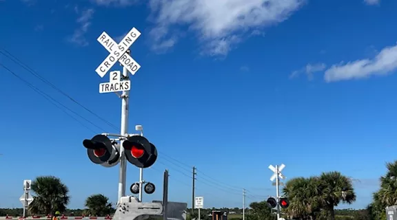 Railroad crossing with safety arms down and lights blinking