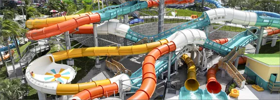 A complex network of brightly colored water slides twists and turns through a large outdoor water pa