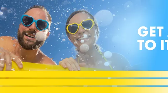 couple with sunglasses smiling with words get away to it all above a image of a train