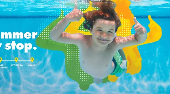 A boy giving two thumbs up while underwater at the pool. 