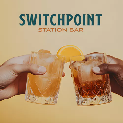 Two people holding cocktails with the caption Switchpoint Station Bar