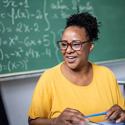 Female teacher with glasses sitting in classroom.