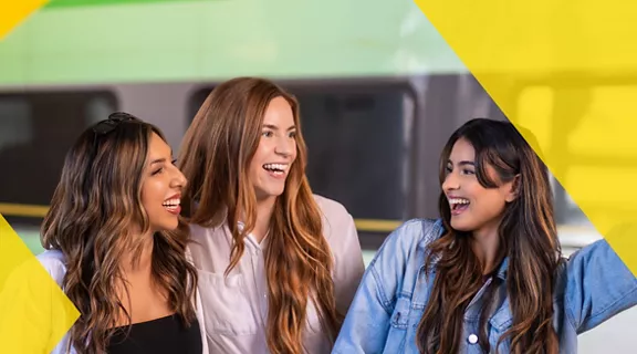 Three women laughing and smiling on the Brightline train platform.