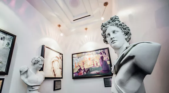 An art gallery featuring classic paintings and statues.