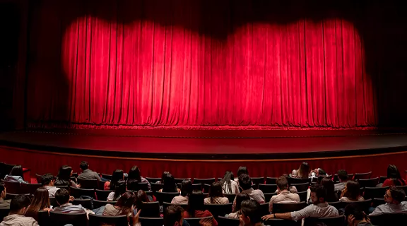 A crowd sitting at a theater, waiting for a performance to begin.