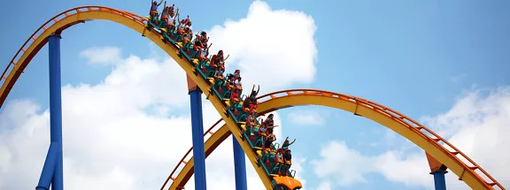 A group of people riding a rollercoaster on a sunny day