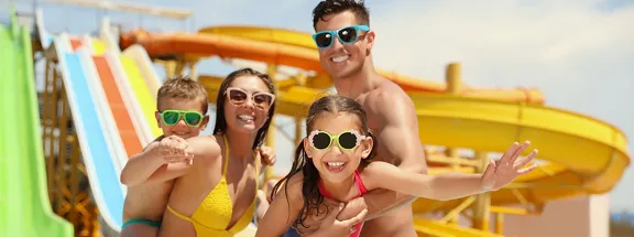 A mom and dad posing for a photo with their two children at a water park.