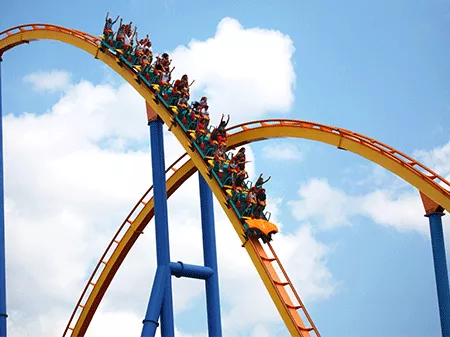 A group of people riding a rollercoaster on a sunny day