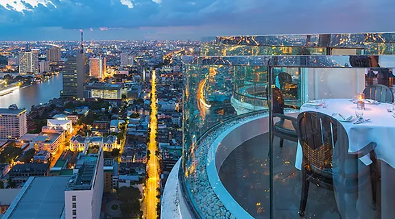 A rooftop restaurant table overlooking a busy city at dusk