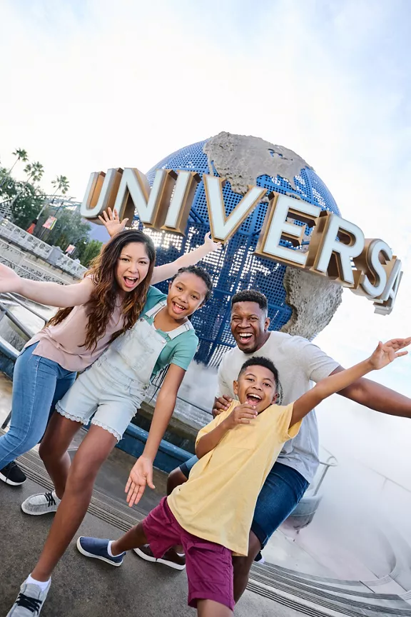 A family of four posing for a picture outside the Universal Studios globe.