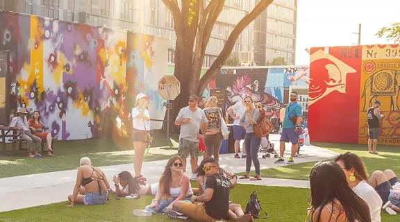 A group of people hanging out at the park admiring the wall of art
