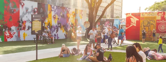 A group of people hanging out at the park admiring the wall of art