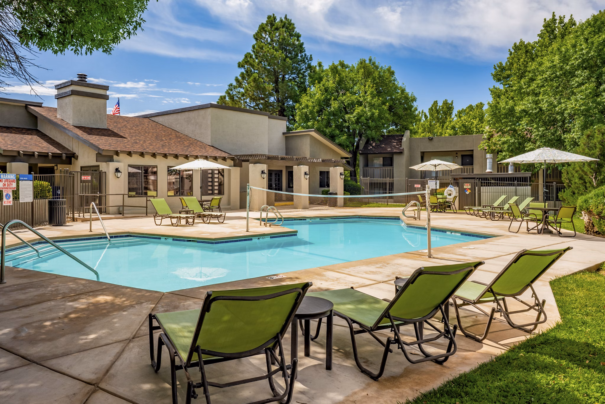 Relaxing poolside retreat at Eagle Point Apartments featuring lush gardens and sun loungers