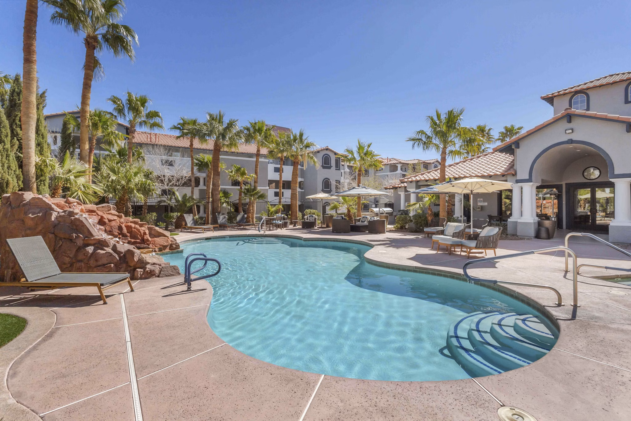Pool with resort-style lounge chairs at Destinations Pebble Apartments, offering luxurious relaxation