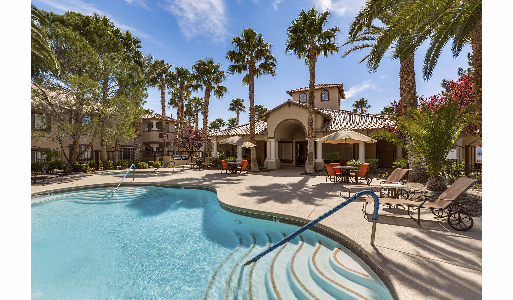 Resort-style pool at Destinations Pueblo Apartment Homes offers luxury relaxation, featuring sun loungers and palm tree surroundings