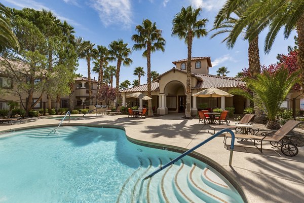 Resort-style pool at Destinations Pueblo Apartment Homes offers luxury relaxation, featuring sun loungers and palm tree surroundings