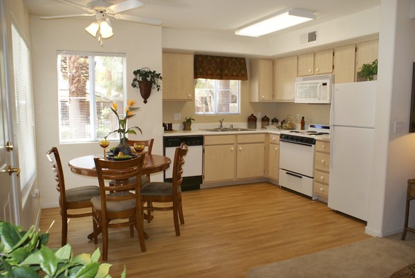 Modern kitchen and dining area with light wood cabinets and a round table in luxury apartment