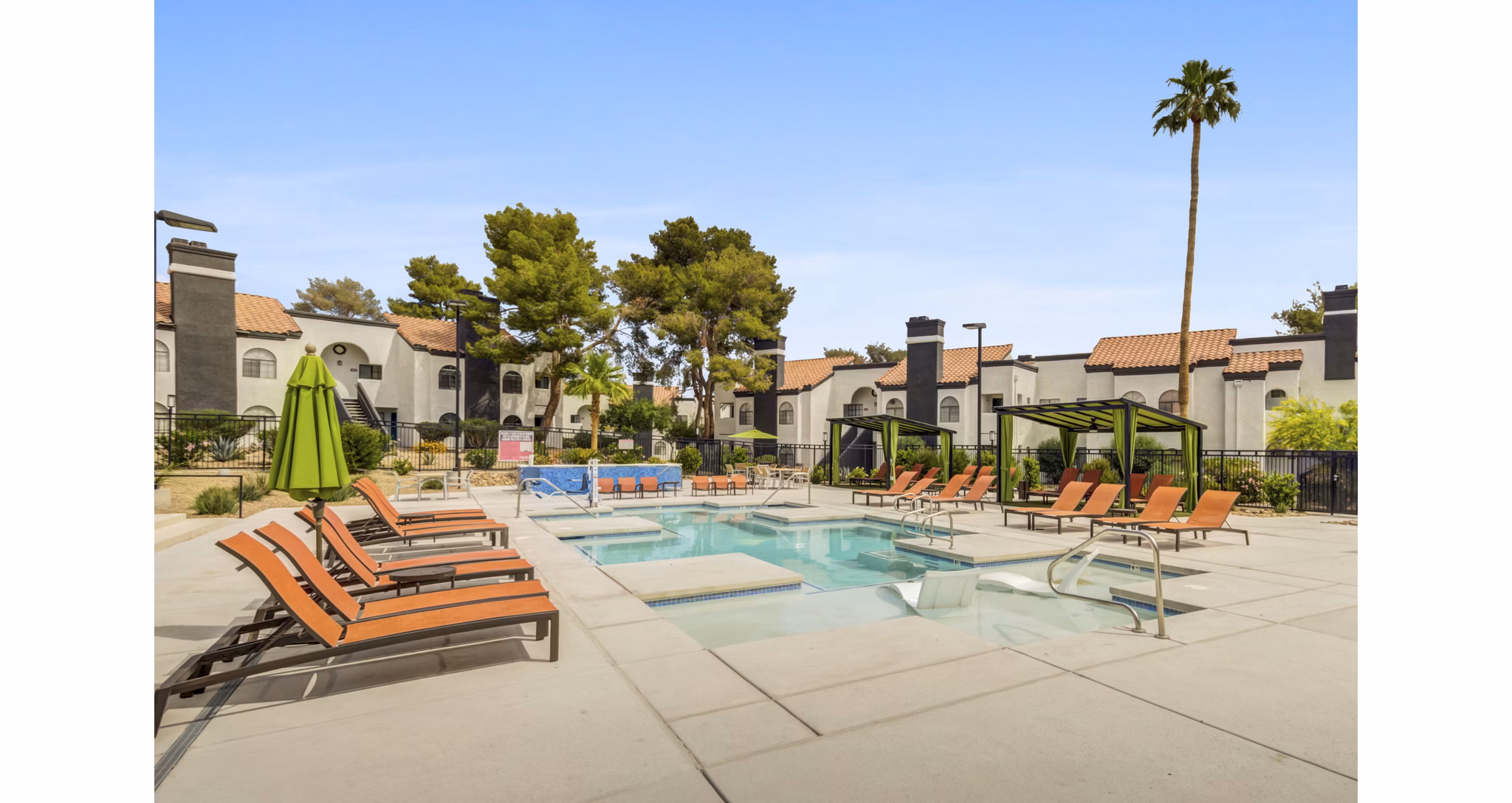 Relaxing poolside area at Bay Court at Montego Bay Apartments with lush landscaping and lounge seating