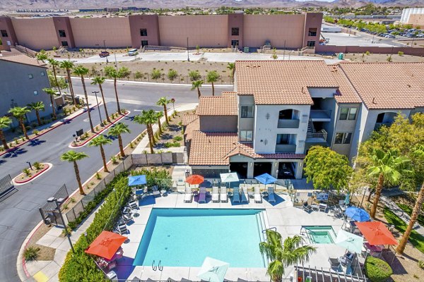 Luxury apartment complex featuring a sparkling swimming pool surrounded by lounge chairs and palm trees