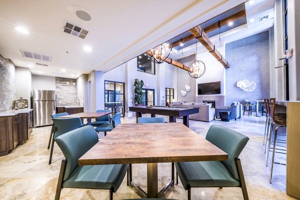 Modern communal space with tables, chairs, pool table, and kitchen in luxury apartment community