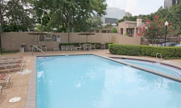 Outdoor swimming pool at Sendera at Greenway Apartments featuring lounge chairs and lush greenery