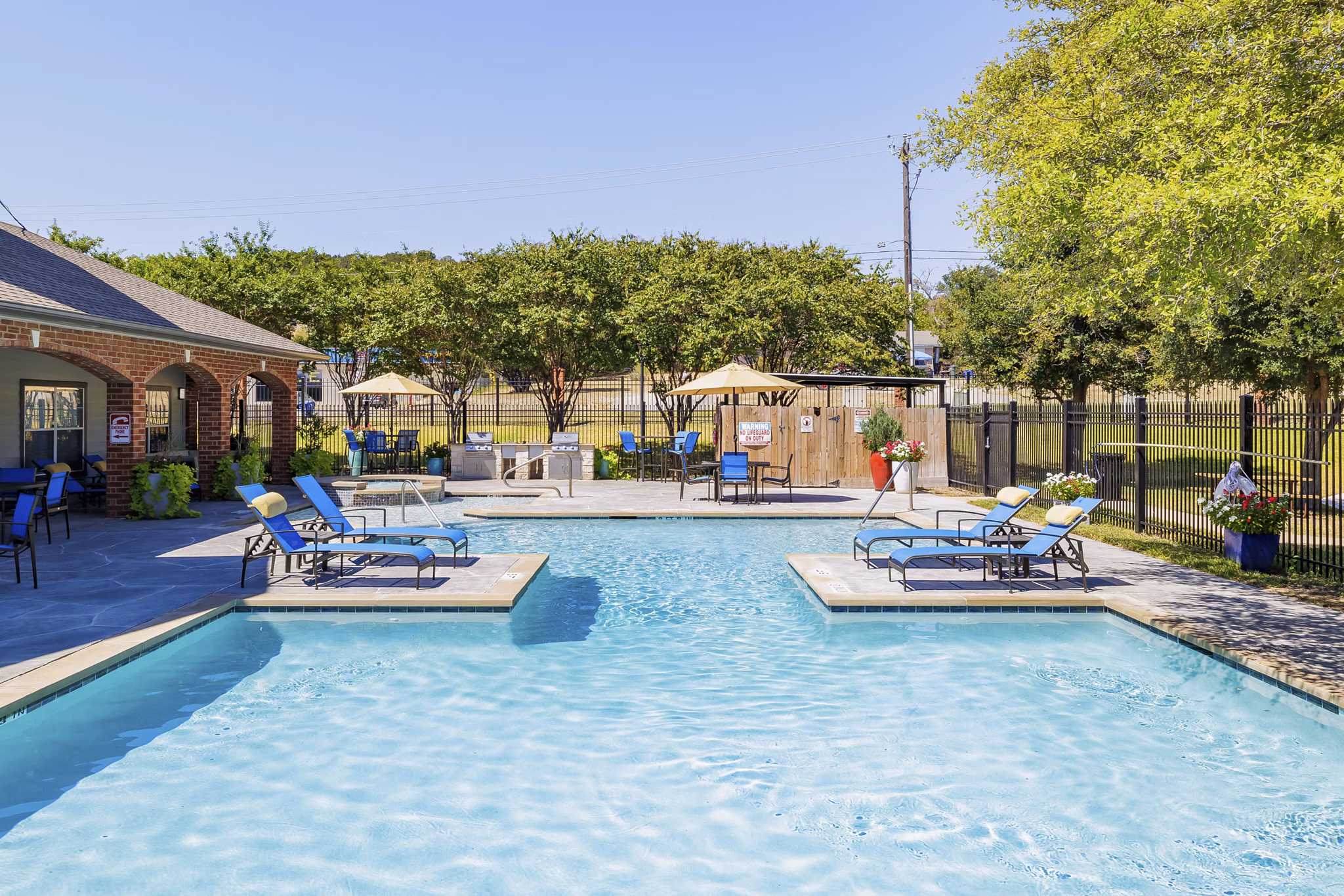 Outdoor swimming pool at Clear Creek Meadows Apartments featuring comfortable loungers and lush landscaping