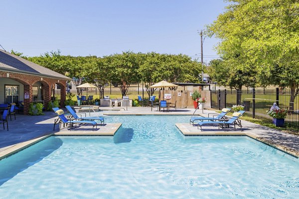 Outdoor swimming pool at Clear Creek Meadows Apartments featuring comfortable loungers and lush landscaping
