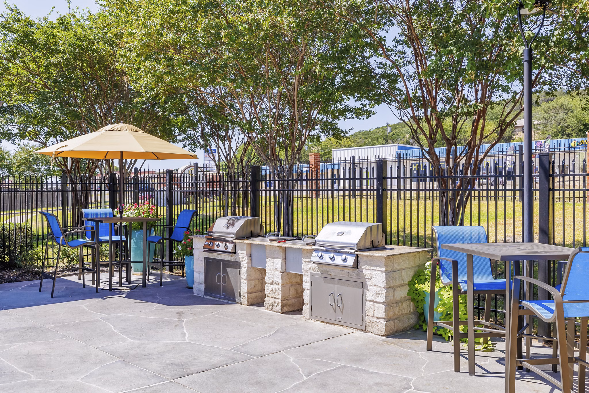 Outdoor grill area at Clear Creek Meadows Apartments featuring modern BBQ stations and seating in a tranquil setting